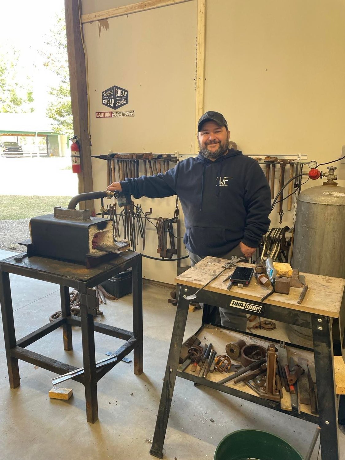 David McConnell stands among the tongs, hammers and other tools made and used by him in his forge. McConnell has made most items in his workshop.